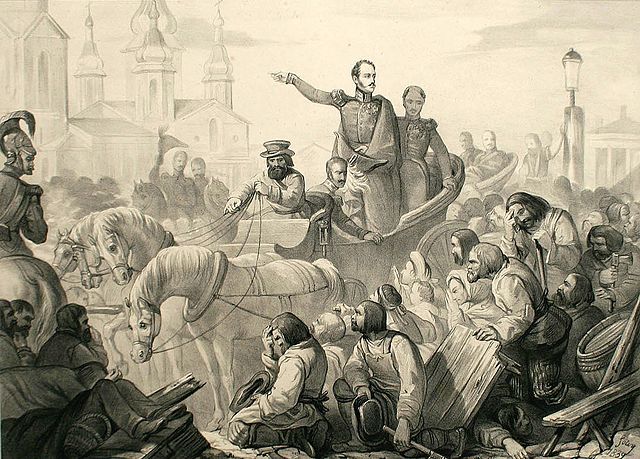 De tsaar die in paard en wagen tussen een woelige mensenmassa door rijdt. Hij spreekt de menigte toe en de mensen buigen voor hem.
