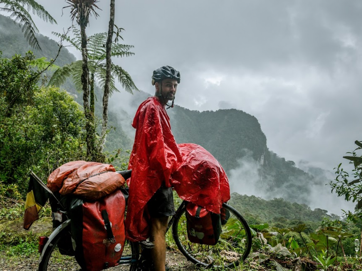 Olivier Van Herck fietst door Colombia. Hij beschermt zich tegen de regen met een poncho, al blijven de tassen niet gespaard door het regenseizoen.